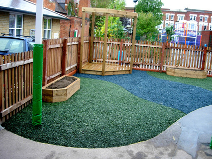 Reception play area showing raised beds, stage with pergola, and recycled rubber safety surface